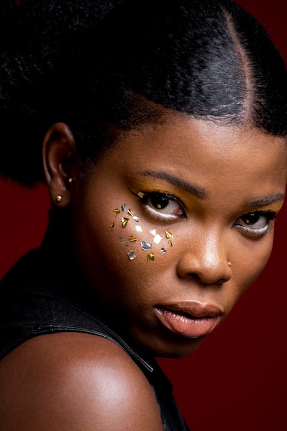 Stylish african woman in leather vest with shiny confetti on her cheeks