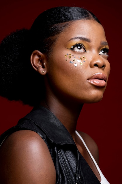 彼女の頬に光沢のある要素を持つ革のベストのスタイリッシュなアフリカの女性