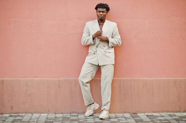 Free photo stylish afro man in beige old school suit against pink wall fashionable young african male in casual jacket on bare torso