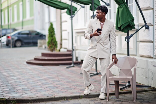 휴대 전화와 베이지색 구식 정장에 세련 된 아프리카 남자 맨 몸통에 캐주얼 재킷에 유행 젊은 아프리카 남성