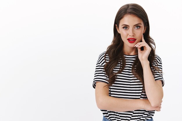 Stylish alluring modern caucasian woman wears red lipstick, striped t-shirt listen team members advice managing business touch cheek look thoughtful, ponder choices