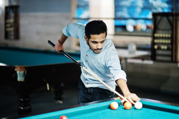 Stylish arabian man wear on jeans playing pool billiard on bar