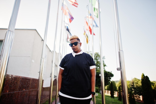 Stylish arabian muslim boy with originally hair posed on streets against flags of different countries