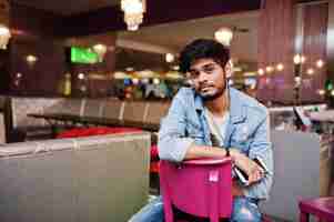 Free photo stylish asian man wear on jeans jacket sitting on chair against bar in club.