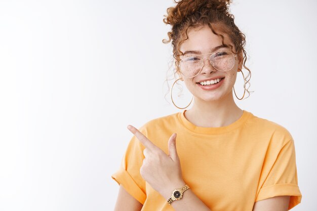 Стильная привлекательная беззаботная рыжая студентка колледжа-подростка, весело улыбаясь, широко улыбаясь, наслаждаясь вечеринкой, девушки правят миром рок-н-ролла жест, ухмыляясь, в модных очках оранжевая футболка