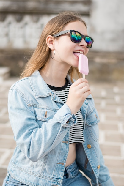 Foto gratuita elegante ragazza moderna attraente che lecca gustoso gelato