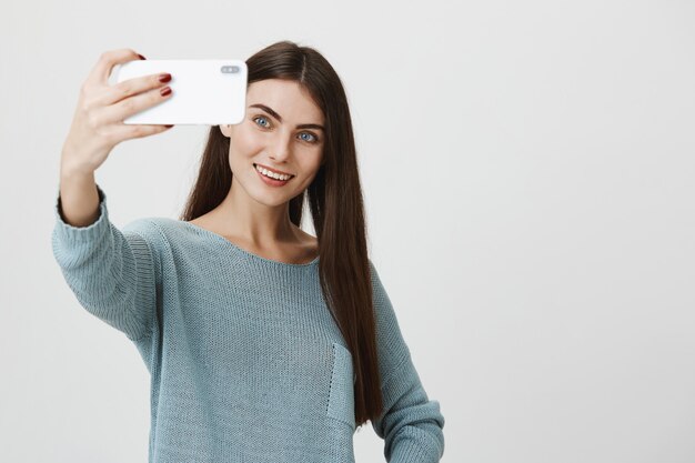 Stylish attractive woman smiling, taking selfie