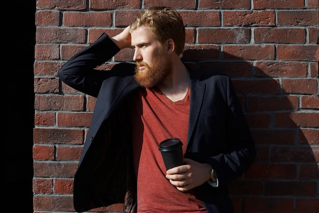 L'uomo alla moda della barba beve il caffè