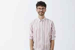 Free photo stylish bearded guy posing against the white wall with glasses