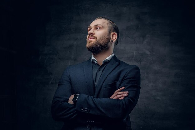 A stylish bearded hipster male dressed in a suit and sunglasses over dark grey background.