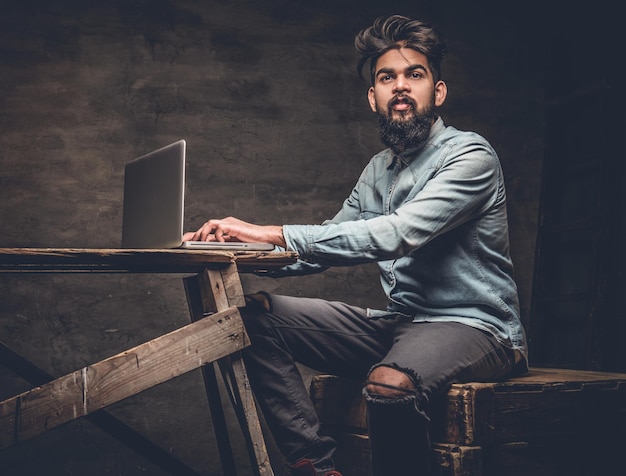 Stylish bearded Indian male working with laptop.