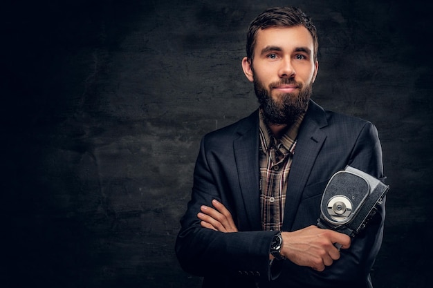 Free photo a stylish bearded male dressed in a suit holds vintage 8mm video camera.