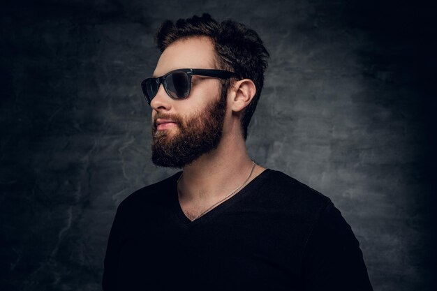 Stylish bearded male in sunglasses over grey background.