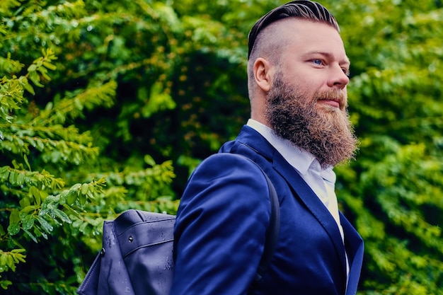 Stylish bearded male with backpack in a city park.