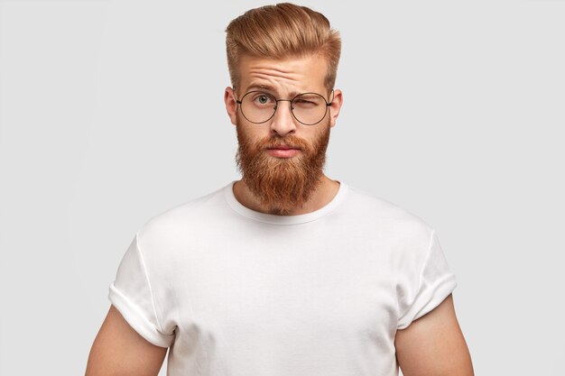 Stylish bearded man frowns face in bewilderment, being dissatisfied with something