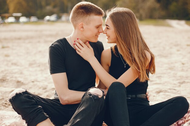 A stylish and beautiful couple in black clothes spends a good time on the beach