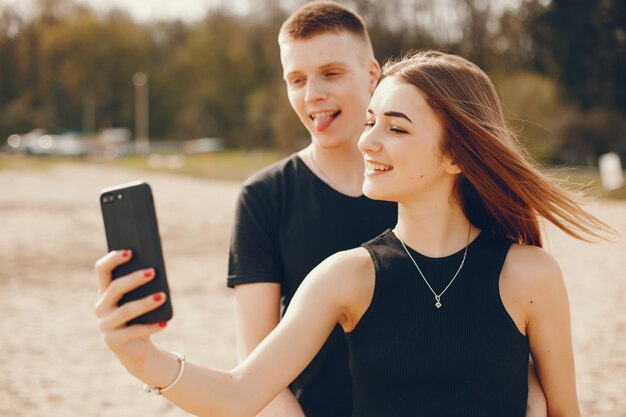 A stylish and beautiful couple in black clothes spends a good time on the beach