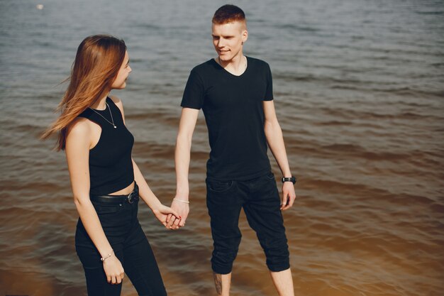 A stylish and beautiful couple in black clothes spends a good time on the beach