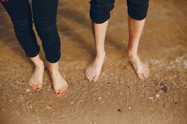 A stylish and beautiful couple in black clothes spends a good time on the beach