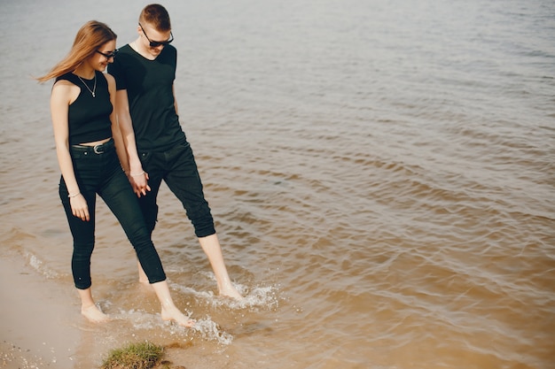 Стильная и красивая пара в черной одежде хорошо проводит время на пляже