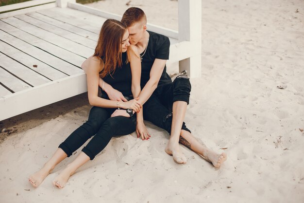 A stylish and beautiful couple in black clothes spends a good time on the beach