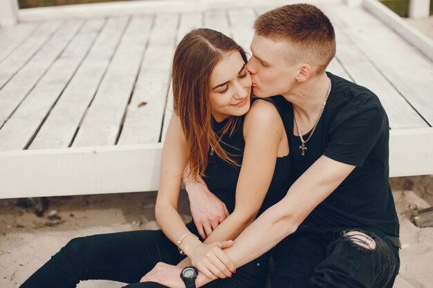 A stylish and beautiful couple in black clothes spends a good time on the beach