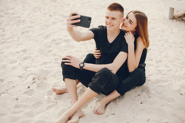 A stylish and beautiful couple in black clothes spends a good time on the beach