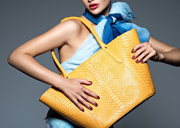 Stylish beautiful woman wearing blue scarf with yellow handbag. fashion model Free Photo