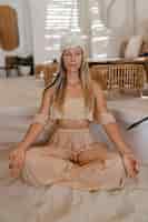 Бесплатное фото Стильная блондинка с тюрбаном в одежде в богемном стиле бохо женщина с длинными волосами практикует асаны йоги