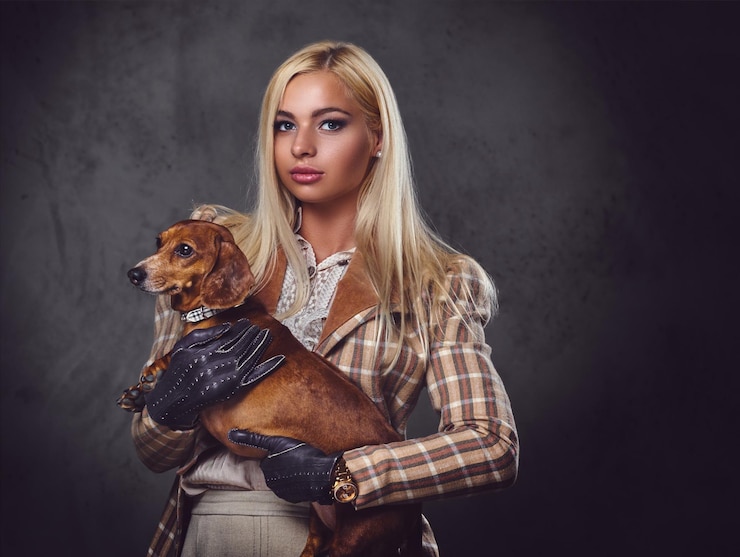 Free Photo a stylish blonde female dressed in old fashioned jacket holds a red badger dog.
