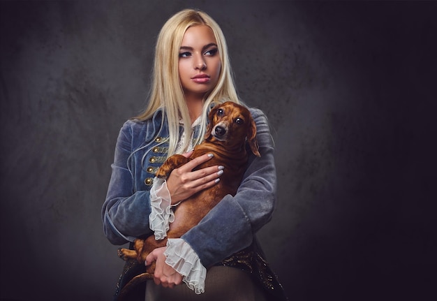 Free photo a stylish blonde female dressed in old fashioned jacket holds a red badger dog.