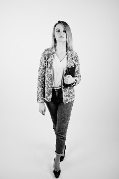 Stylish blonde girl in jacket and jeans with notebook diary at hands against white background on studio