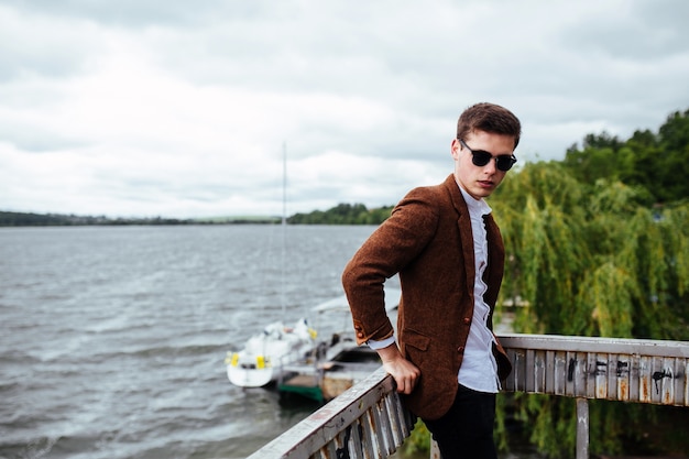 Free photo stylish boy posing with lake background