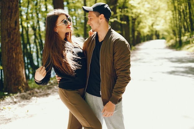 A stylish and bright love couple walks in the sunny forest