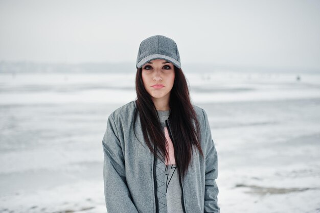 Stylish brunette girl in gray cap casual street style on winter day