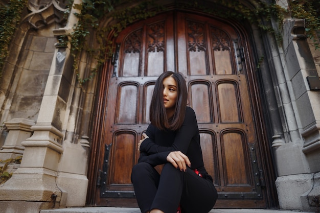 stylish brunette girl sitting on the stairs