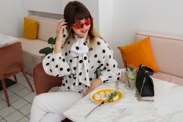 Free photo stylish brunette  woman sitting in cafe and drinking cocktails