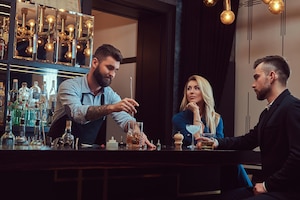 Stylish brutal bartender serves an attractive couple who spend an evening on a date.