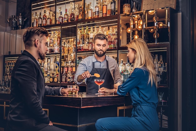Stylish brutal bartender serves an attractive couple who spend an evening on a date.