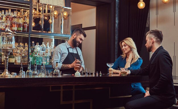 Stylish brutal bartender serves an attractive couple who spend an evening on a date.