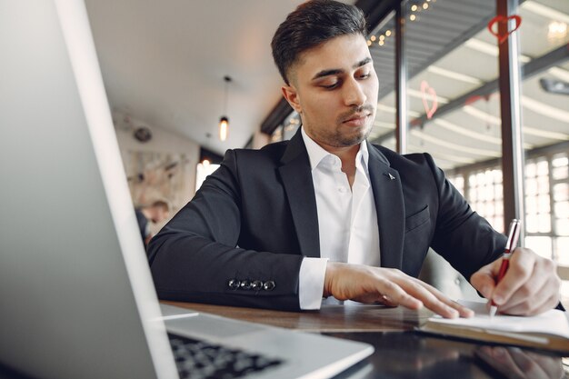 Стильный бизнесмен работает в кафе и использует ноутбук