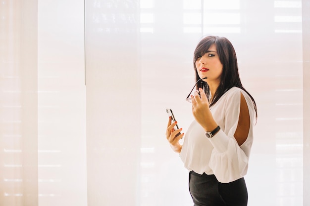 Foto gratuita businesswoman alla moda che presentano con il telefono