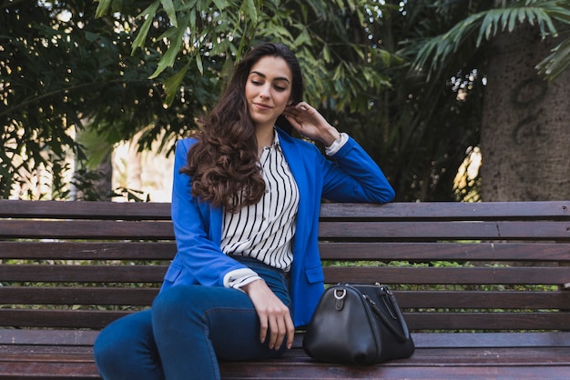 Stylish businesswoman sitting on a park bench