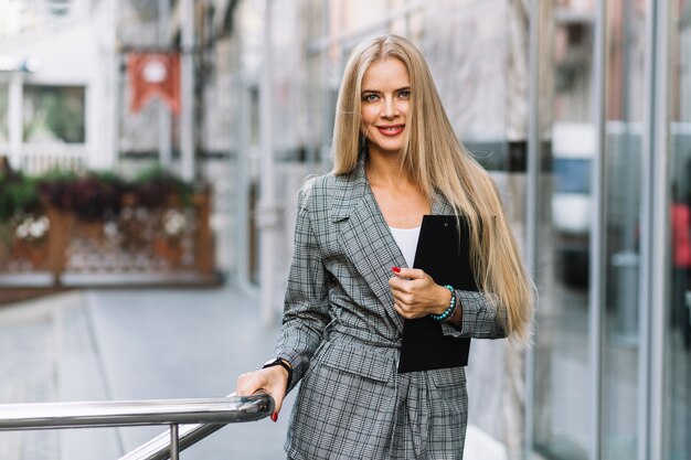 Stylish businesswoman with clipboard in city