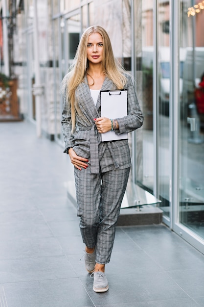 Stylish businesswoman with clipboard in city