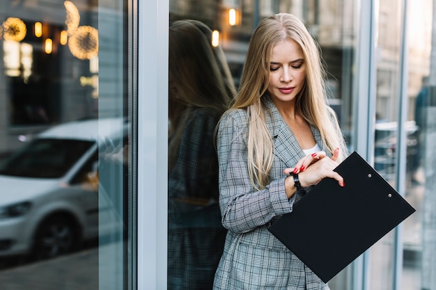 Stylish businesswoman with clipboard in city