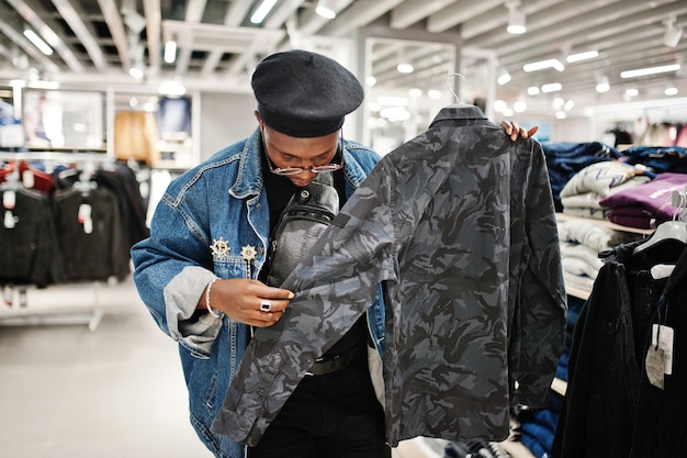無料写真 新しいミリタリーシャツを探しているジーンズのジャケットと洋服店の黒いベレー帽でスタイリッシュなカジュアルなアフリカ系アメリカ人の男
