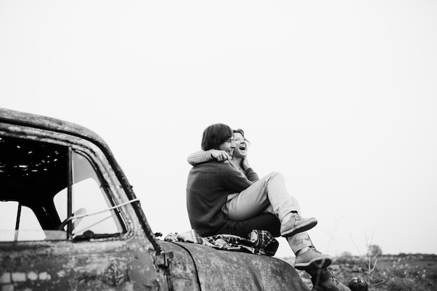 Free photo stylish couple in love sit on the abandoned truck and looks happy