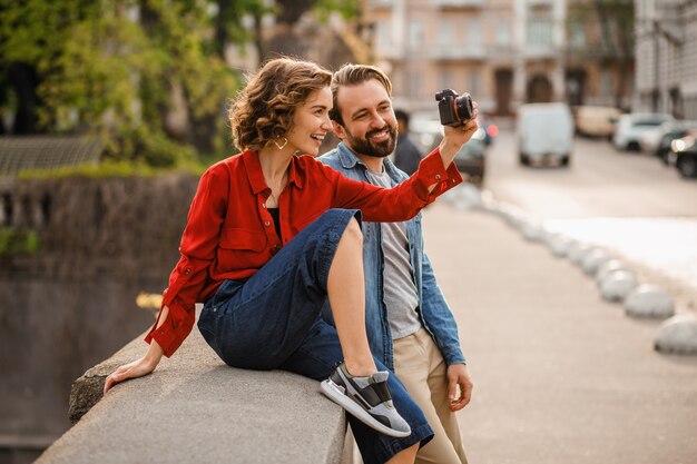 Стильная влюбленная пара, сидя на улице в романтическом путешествии, фотографируя