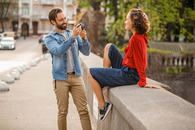 Stylish couple in love sitting in street on romantic trip, taking photo